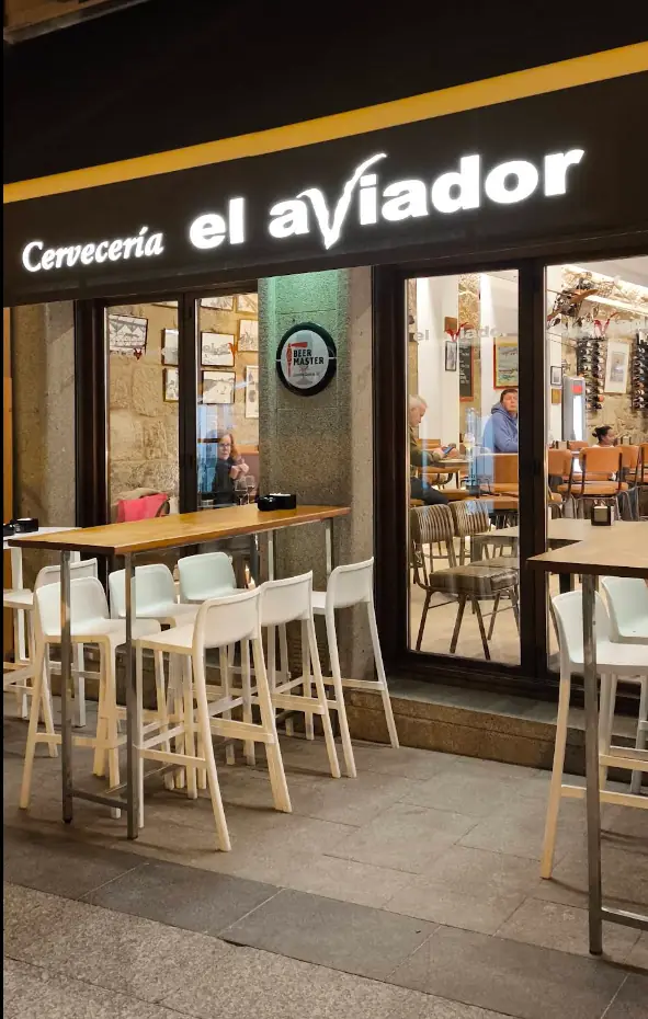 Fachada de Cervecería El Aviador en Sanxenxo, con su rótulo luminoso y las mesas altas de la calle